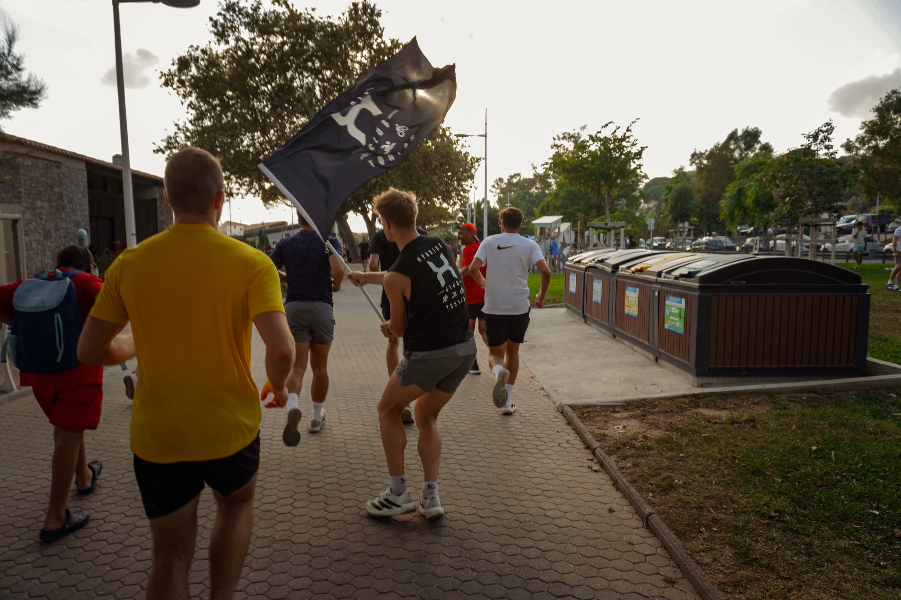 Le groupe du club court avec le drapeau Hybride le long de la promenade du Mourillon, au coucher du soleil