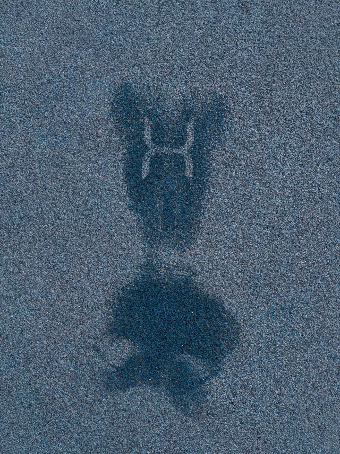 Empreinte humide d’un tee-shirt du club sur le sol de la piste, le logo H resté en clair