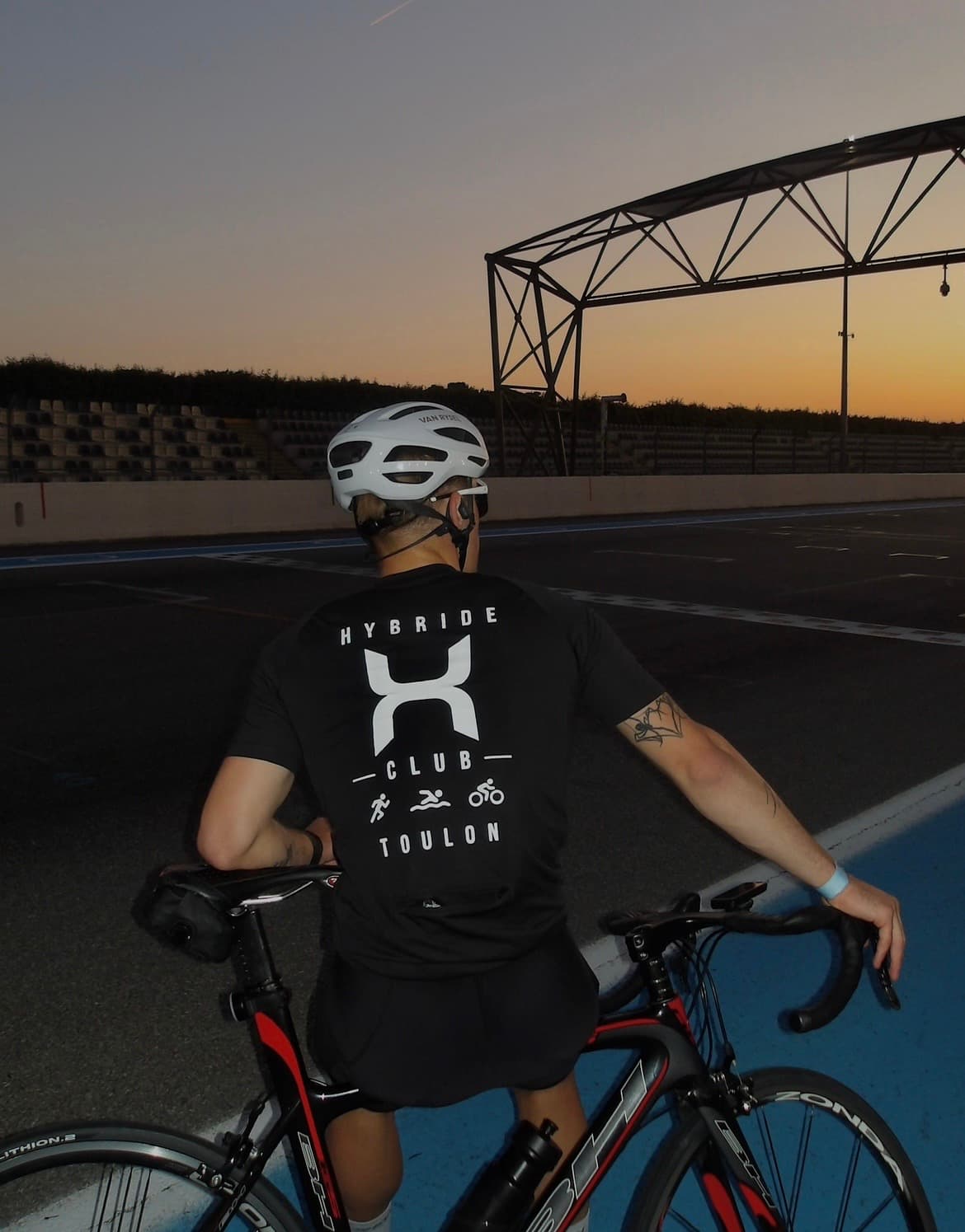 Un membre du club Hybride Toulon avec son vélo sur un circuit, au coucher du soleil